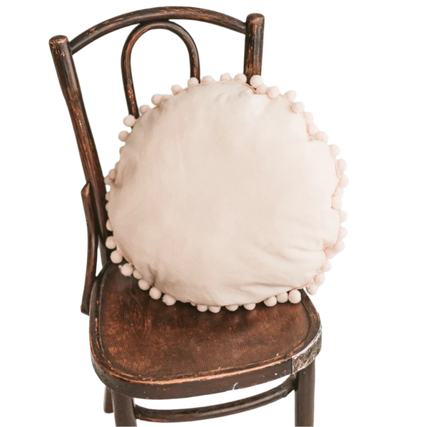 Close-up of the beige cushion’s pompom trim