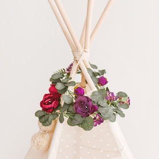 Eucalyptus and peony garland draped over a kid's teepee for boho-inspired decor.